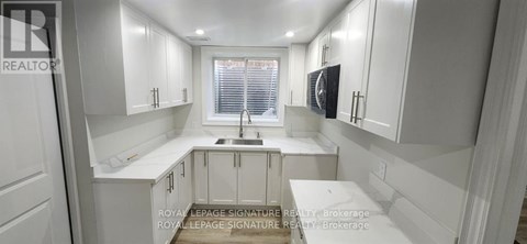 A white kitchen with a sink and cabinets.