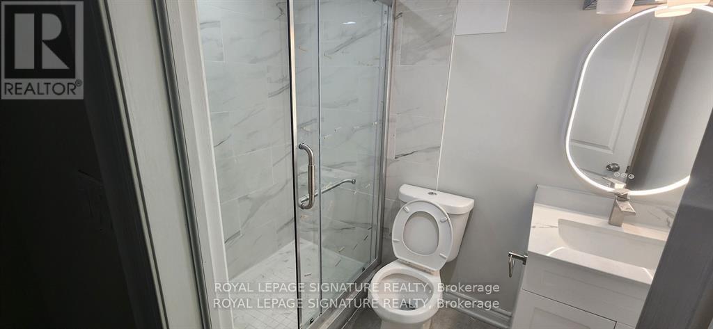 A white toilet is in a small bathroom with a glass shower door.