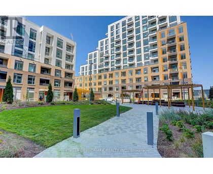 A walkway with a series of posts on it leads through a grassy area between two buildings.