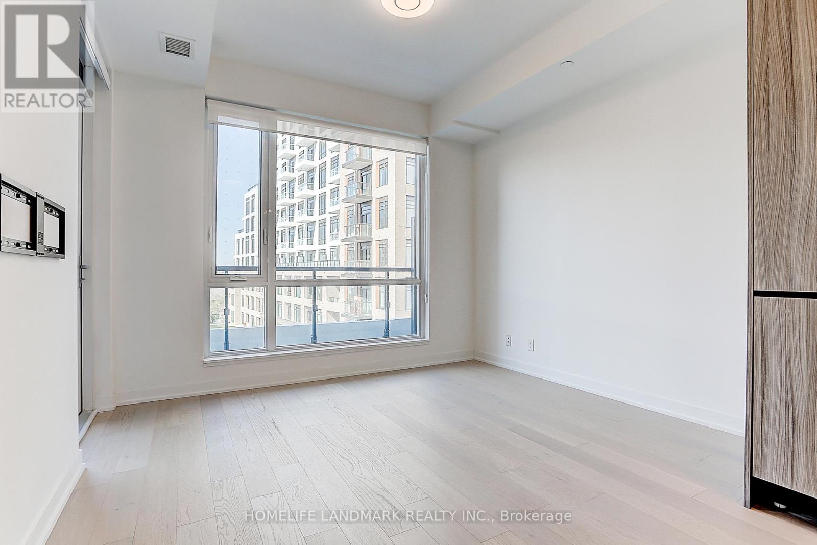 A spacious room with a large window overlooking a cityscape.