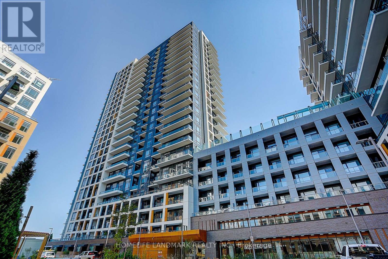 A tall building with a blue and white facade stands in front of other buildings.
