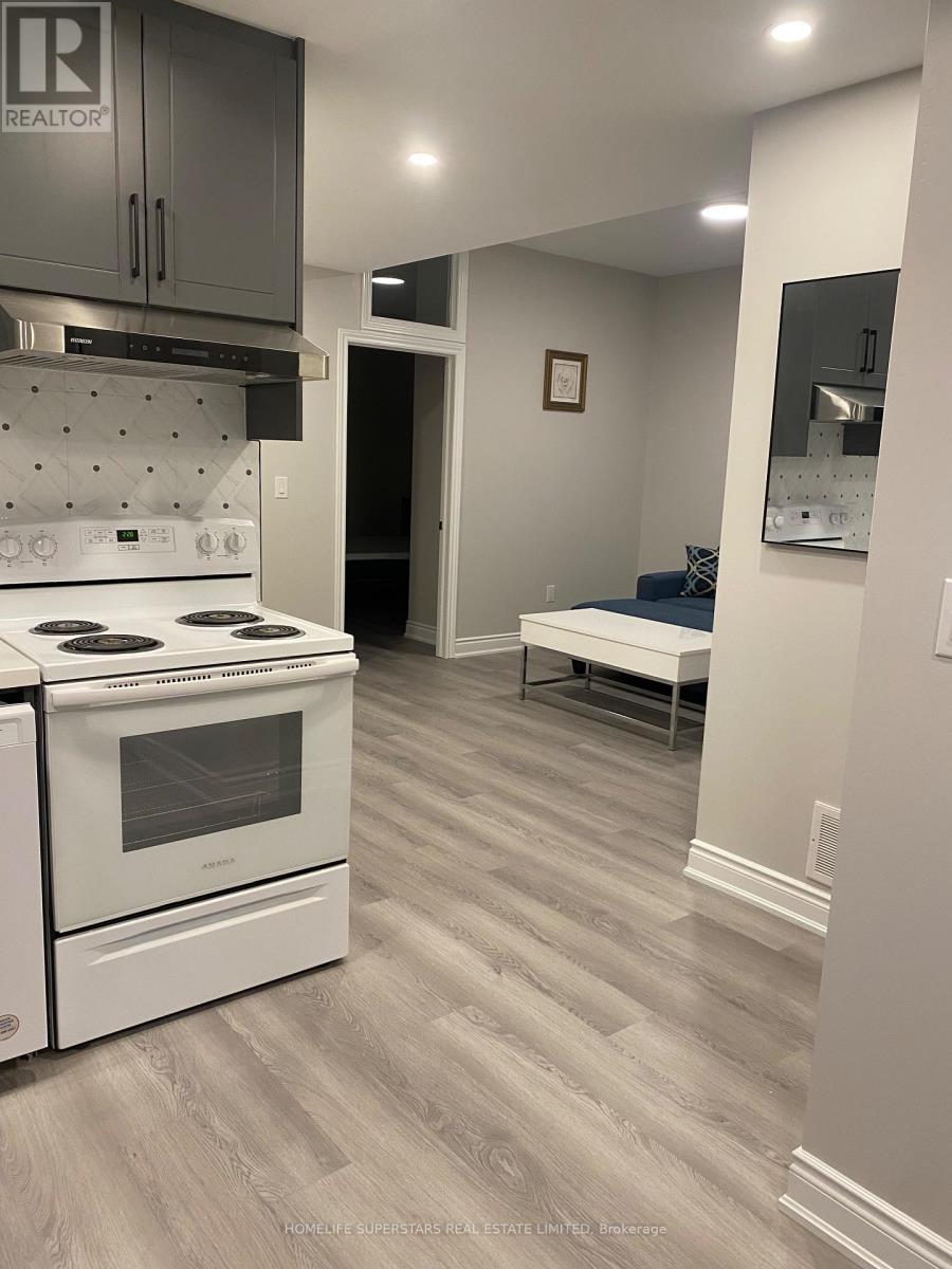 A kitchen with a white stove and grey cabinets.
