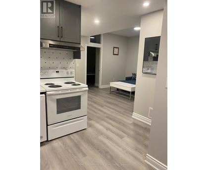 A kitchen with a white stove and grey cabinets.