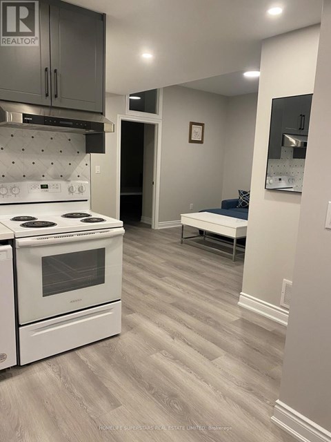 A kitchen with a white stove and grey cabinets.