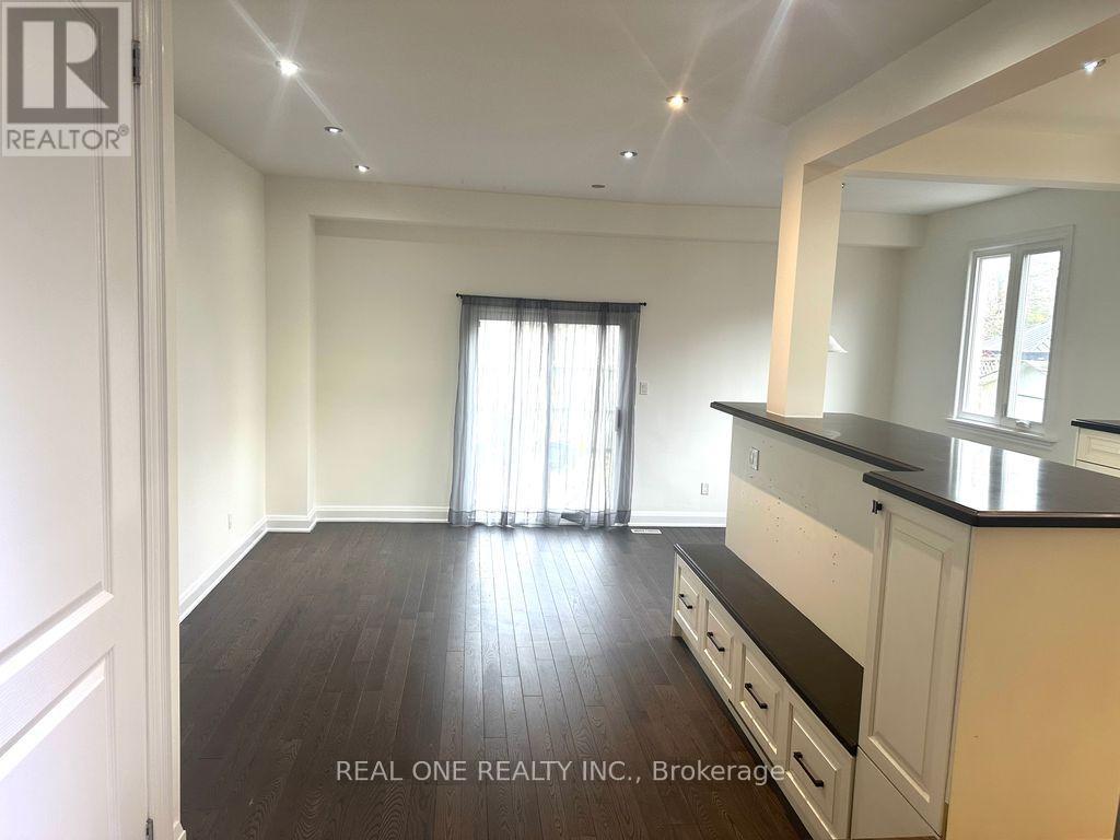 A spacious kitchen with dark wood floors and white cabinets.