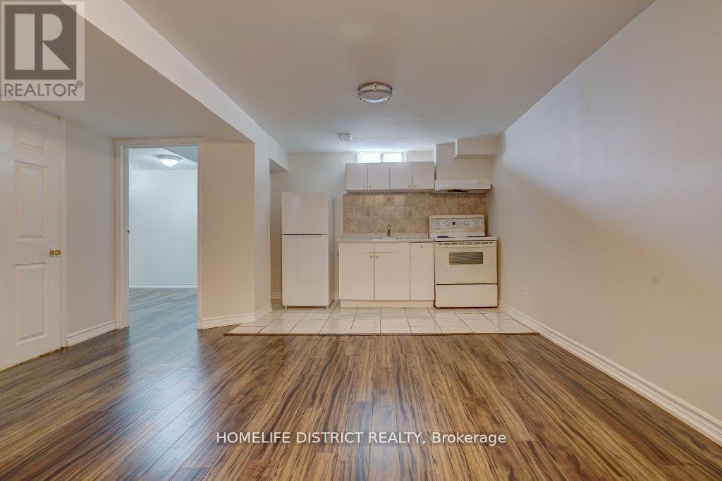 A room with wooden flooring and a kitchenette in the background.