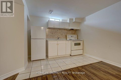 A kitchen with white cabinets and a wooden floor.