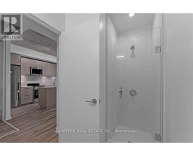 A bathroom with a walk-in shower and a doorway leading to a kitchen.