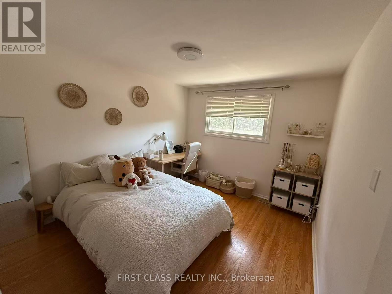 A bedroom with a bed, a desk, and a window.