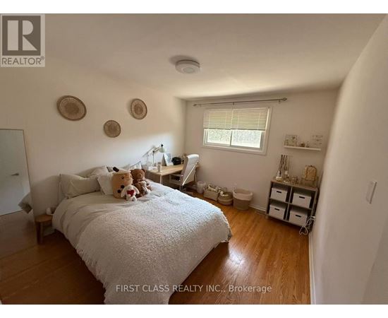 A bedroom with a bed, a desk, and a window.