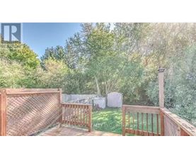 A wooden deck with a lattice fence and a view of a backyard with a shed.