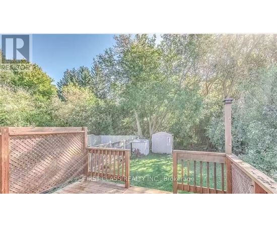 A wooden deck with a lattice fence and a view of a backyard with a shed.