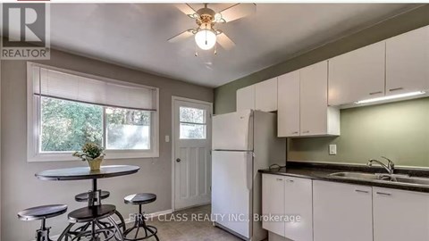 A kitchen with white cabinets and a bar stool.