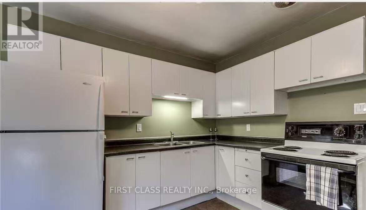 A kitchen with white cabinets and a refrigerator.