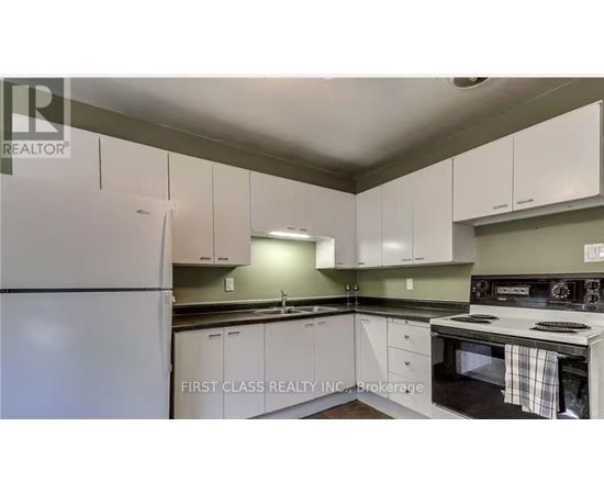 A kitchen with white cabinets and a refrigerator.