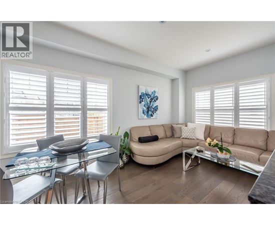 A well-lit living room with a glass dining table and chairs, a sofa, and a coffee table.