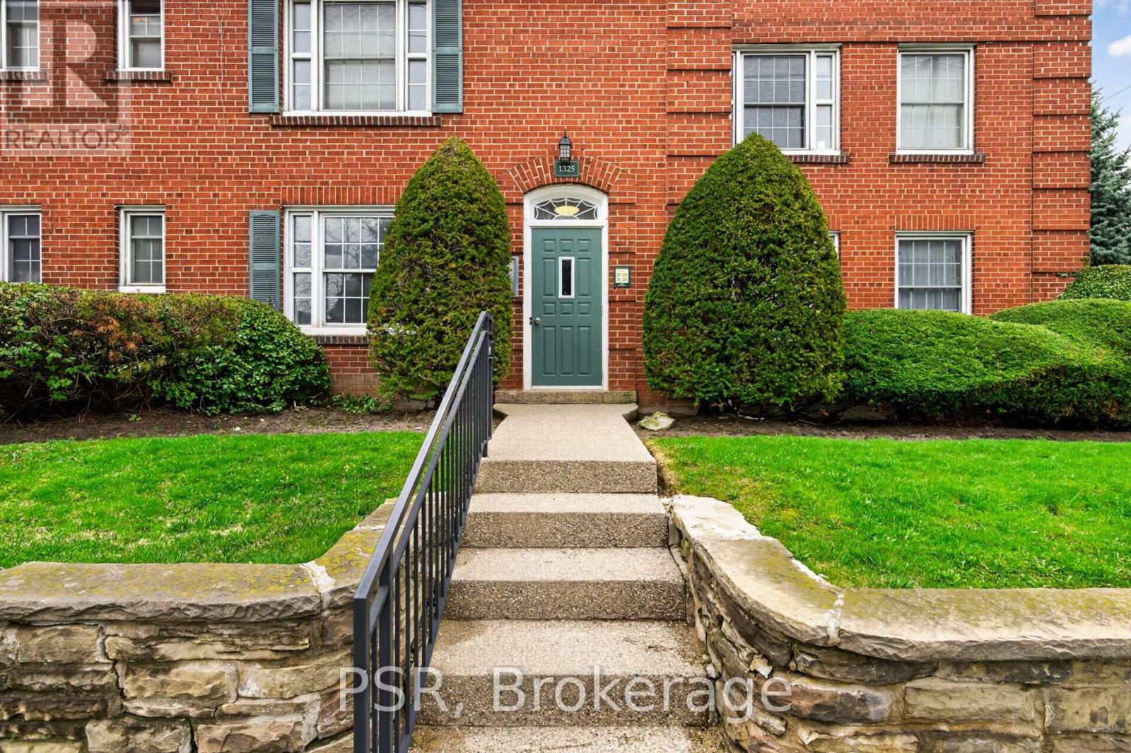 A red brick building with a green door and steps leading up to it.