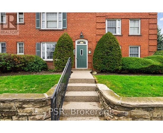 A red brick building with a green door and steps leading up to it.