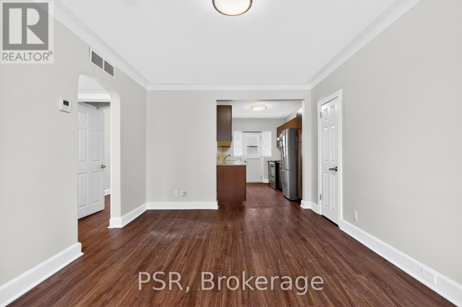 A spacious room with wood flooring and white walls.