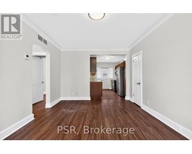 A spacious room with wood flooring and white walls.