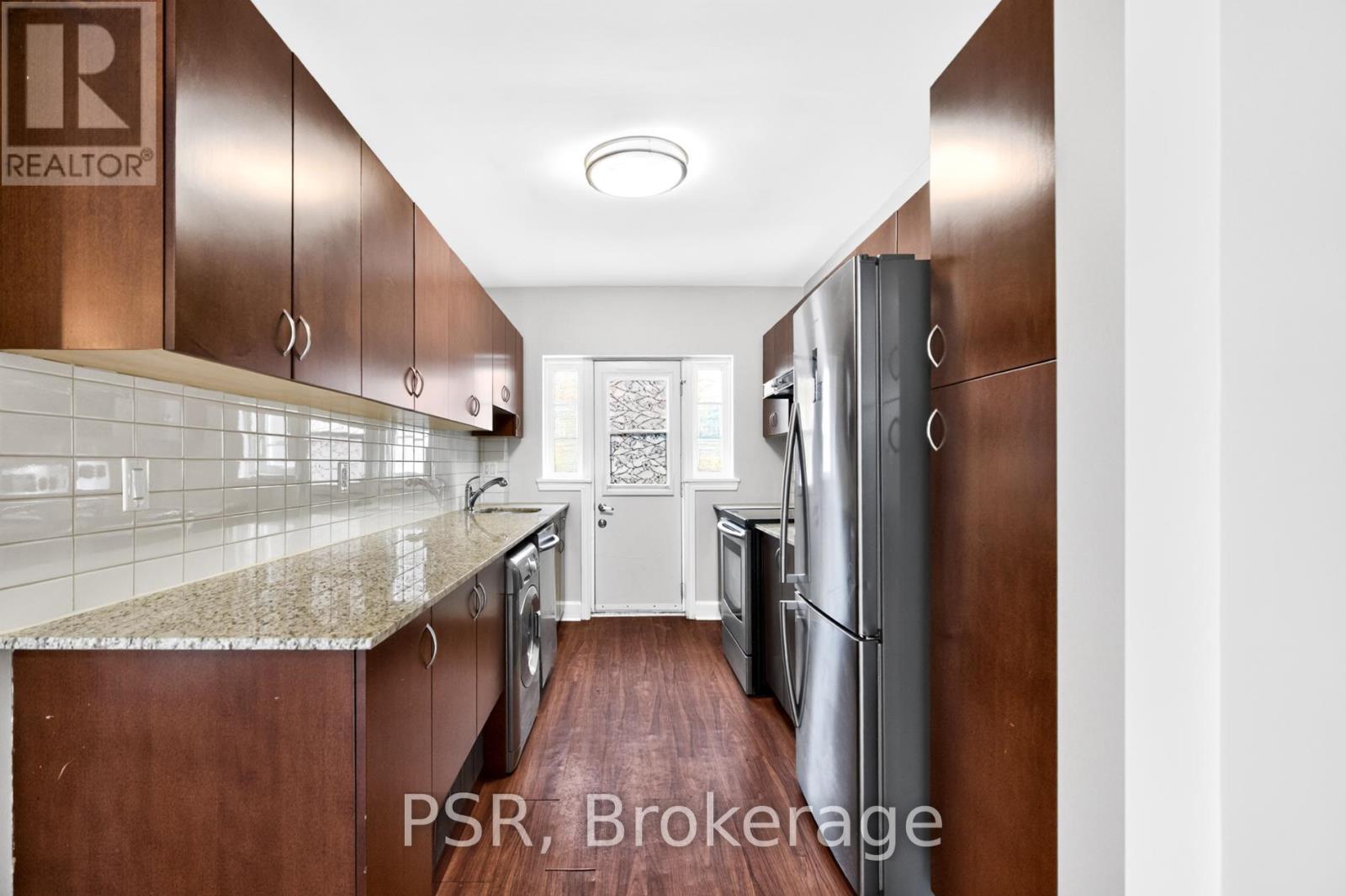 A kitchen with brown cabinets and a marble countertop.