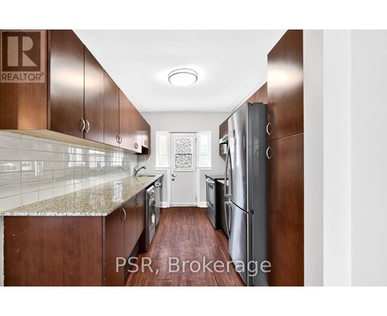 A kitchen with brown cabinets and a marble countertop.