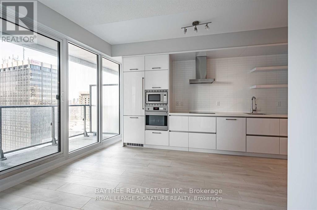 A modern kitchen with white cabinets and appliances, with a view of the city outside the window.