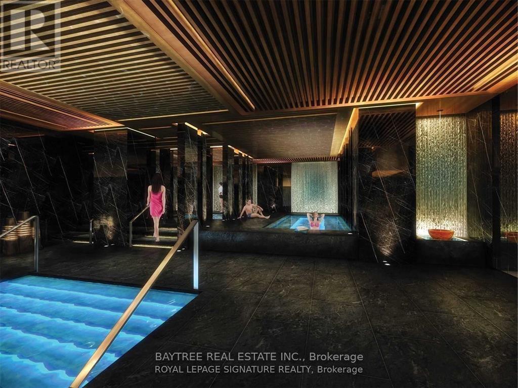 A woman in a pink dress is standing in a spacious room with a blue pool.
