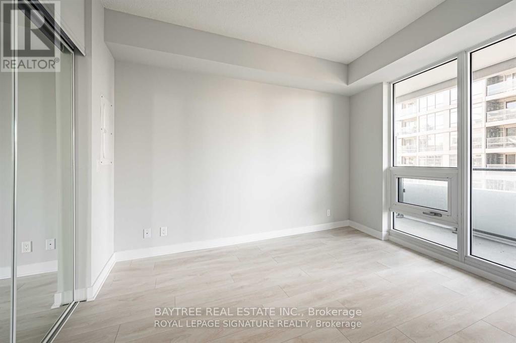 A spacious room with a sliding glass door leading to a balcony.