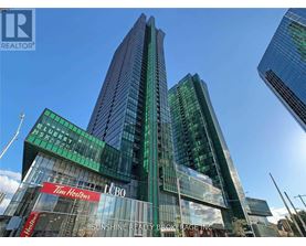 A tall building with a green and blue glass facade and a sign that reads "Sunshine Realty Brokerage Inc.".