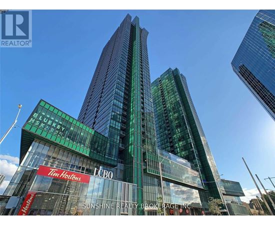 A tall building with a green and blue glass facade and a sign that reads "Sunshine Realty Brokerage Inc.".