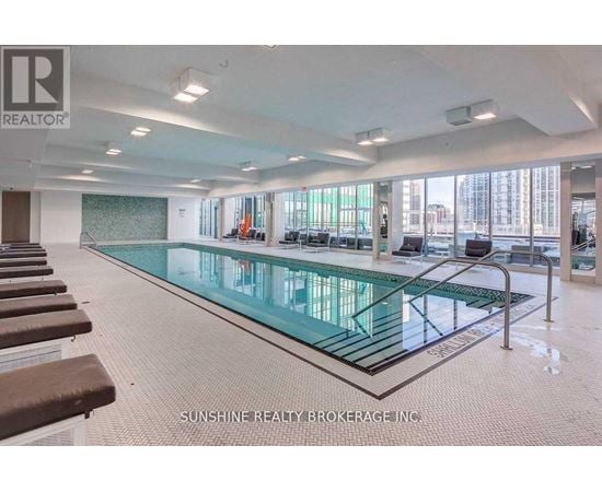 A large indoor swimming pool with a glass bottom and a tiled floor.