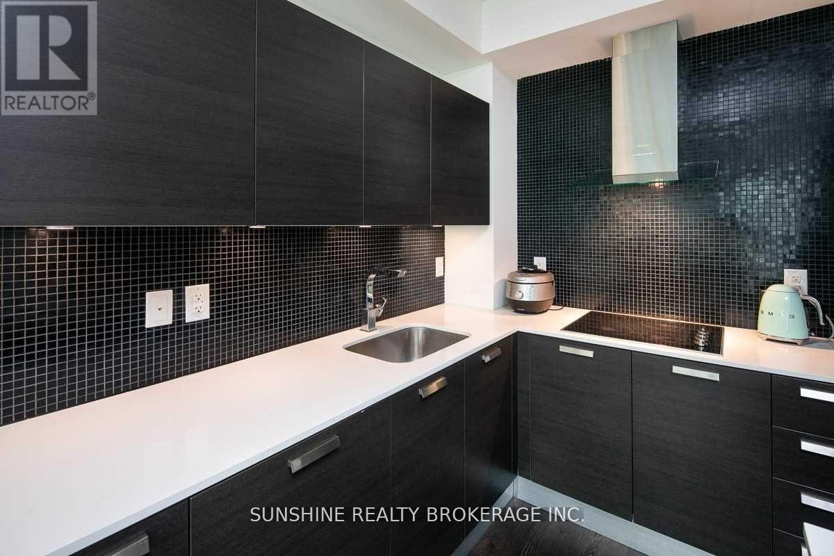 A modern kitchen with black cabinets and a white countertop.