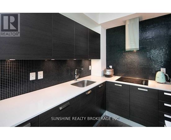 A modern kitchen with black cabinets and a white countertop.