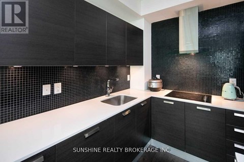 A modern kitchen with black cabinets and a white countertop.