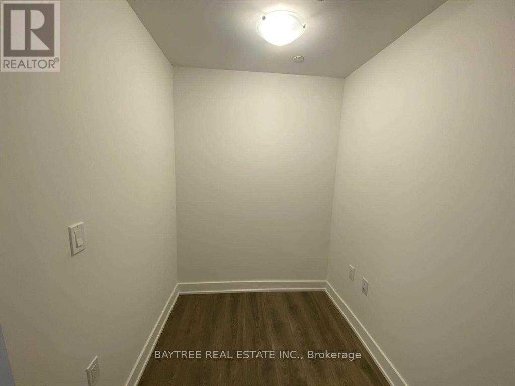 A room with white walls and wooden flooring, with a light fixture on the ceiling.