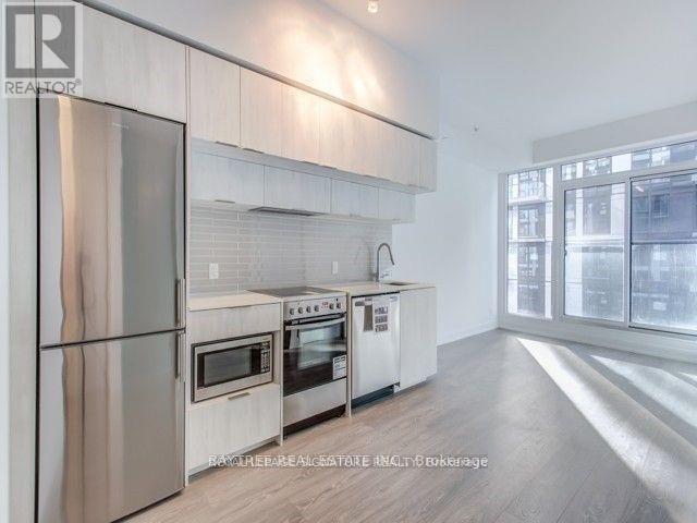 A modern kitchen with stainless steel appliances and wooden flooring.
