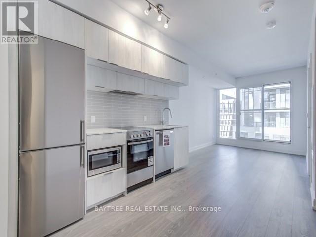 A modern kitchen with stainless steel appliances and wooden floors.