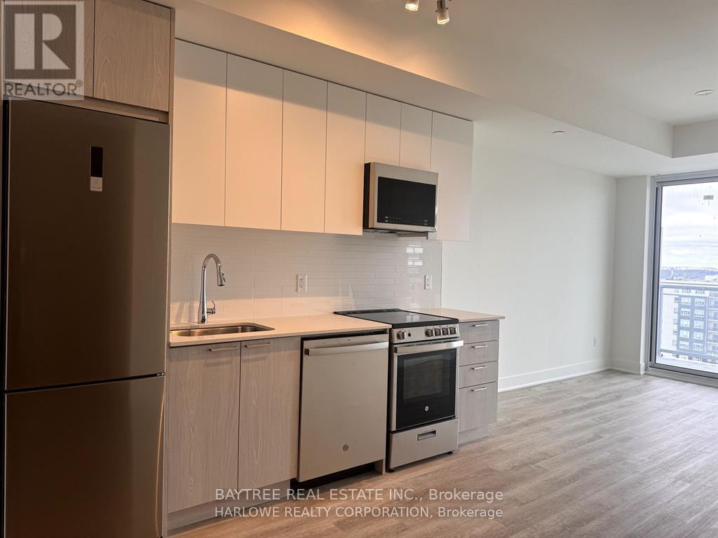 A kitchen with a refrigerator, sink, and stove top oven.