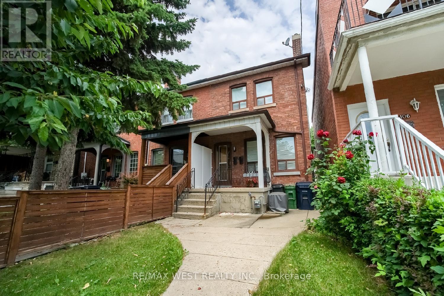 A house with a brown fence and a tree in front of it.