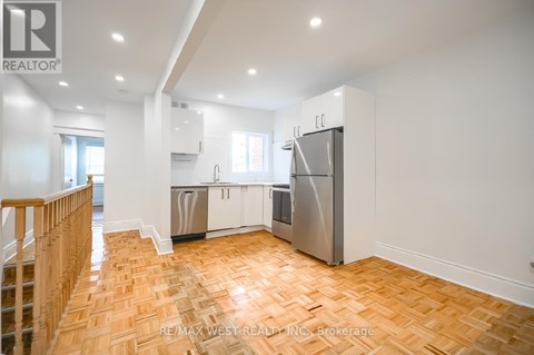A kitchen with a refrigerator, sink, and cabinets.