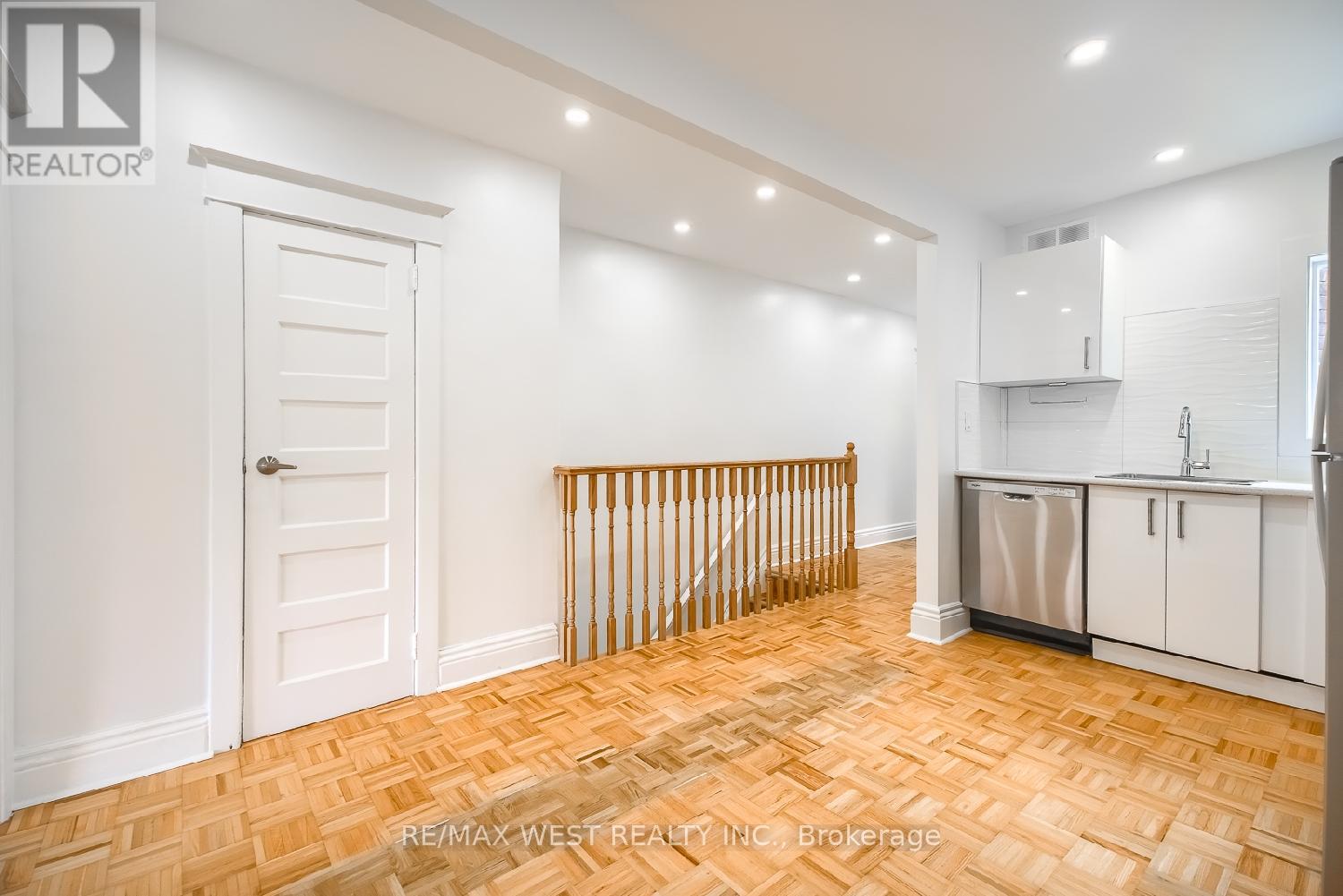 A room with a wooden floor and white walls, with a door and a window blind.