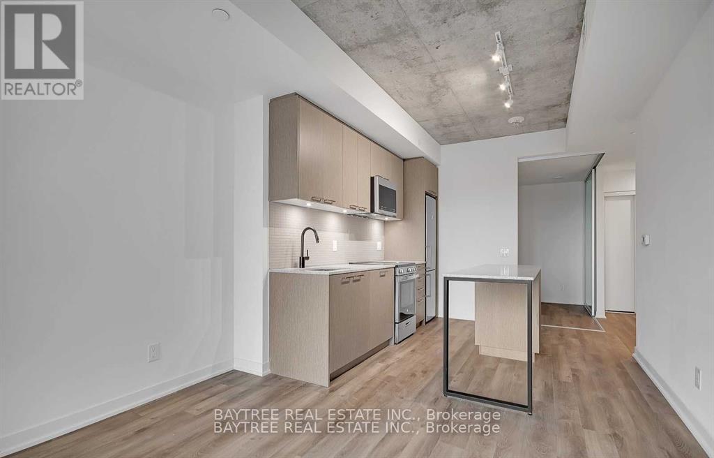 A modern kitchen with wooden floors and a white ceiling.