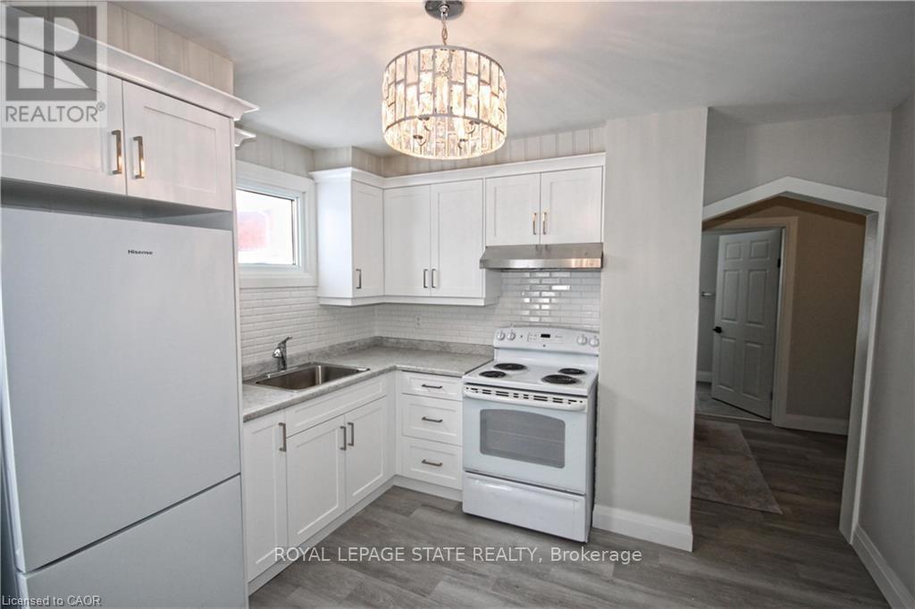 A kitchen with white cabinets and a white stove top oven.