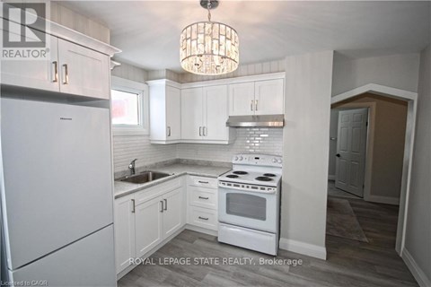 A kitchen with white cabinets and a white stove top oven.