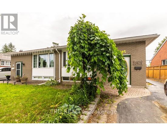 A house with a green lawn and a tree in front of it.