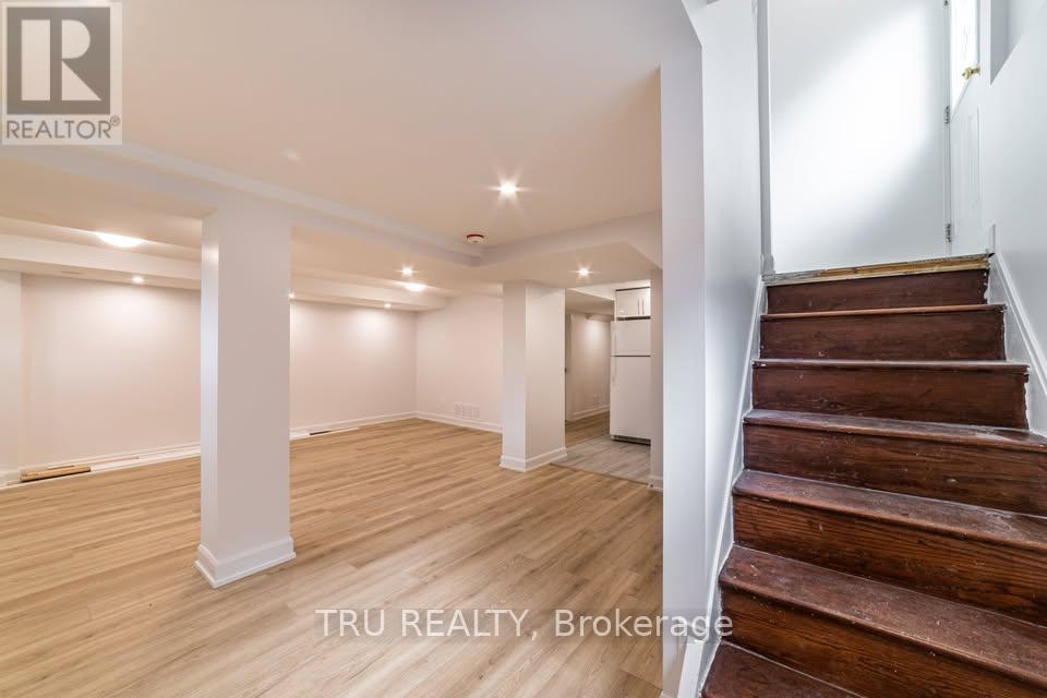 A spacious room with wooden floors and a staircase leading to another level.