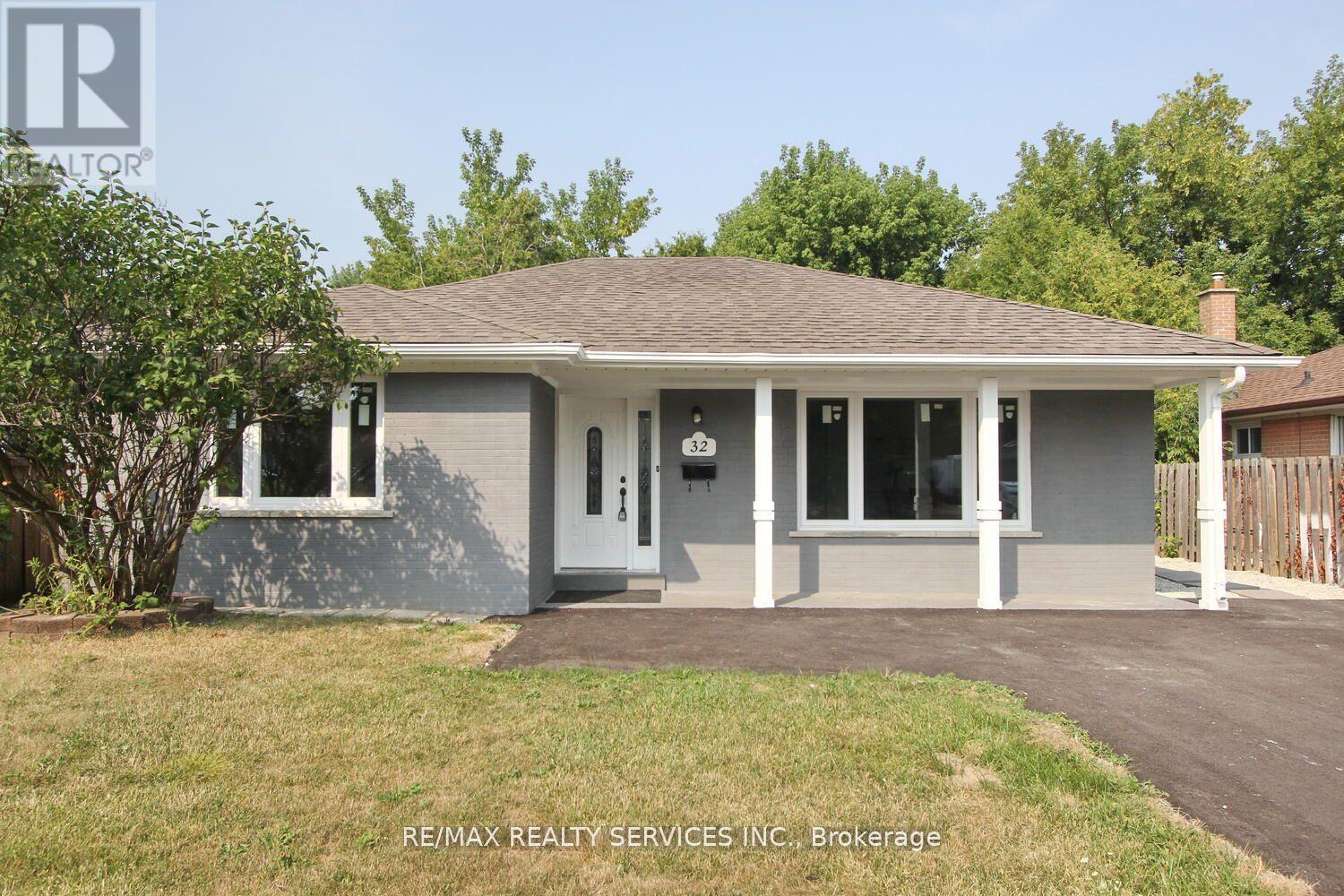 A house with a grey roof and a white fence in front.