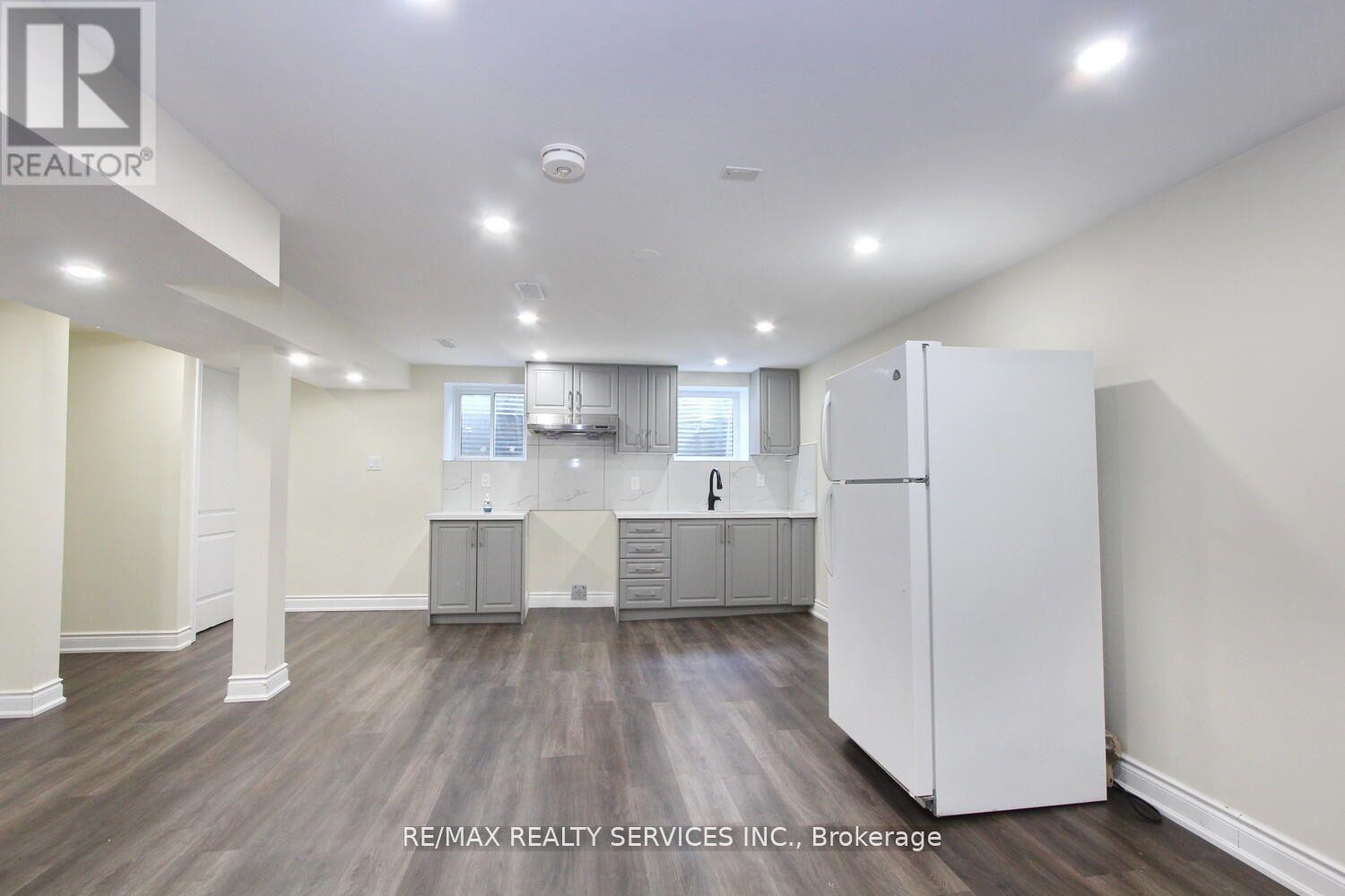 A spacious kitchen area with white appliances and wooden flooring.