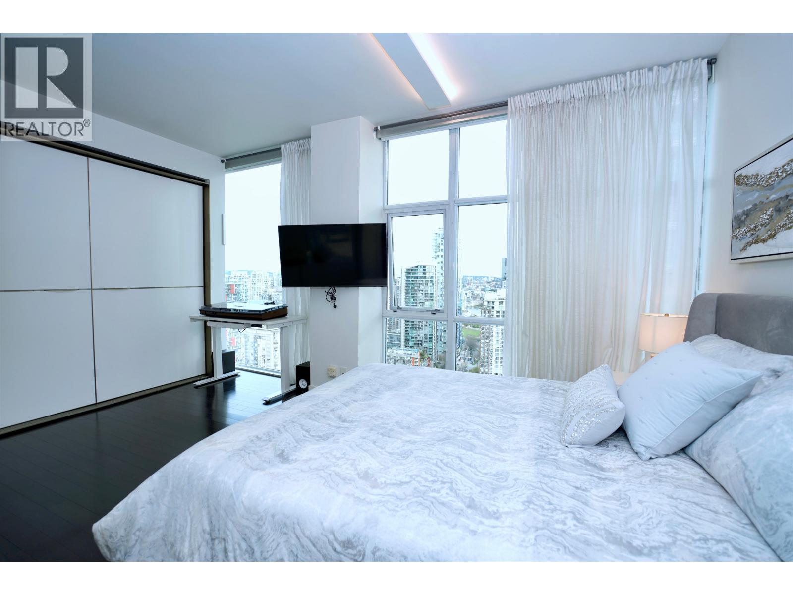 A bedroom with a large bed and a flat screen TV mounted on the wall.